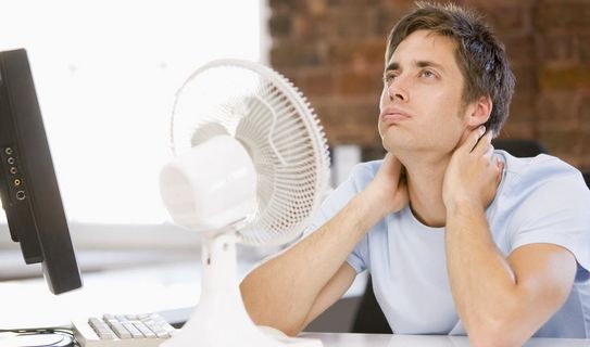 Mann im Büro vor Ventilator