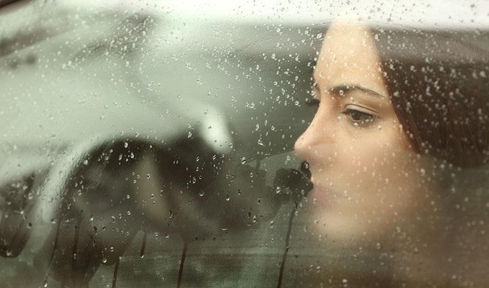 Negative psychische Belastungen erkennen Frau schaut nachdenklich durch beschlagene Autoscheibe