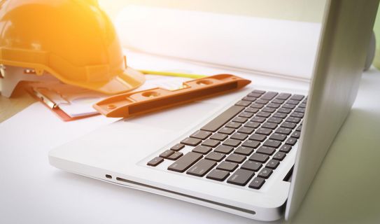 E-Learning mit DENEQUA Aufgeklappter Laptop mit Arbeitsschutzhelm davor