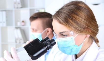 Sicheres Arbeiten mit Biostoffen Laboranten arbeiten am Mikroskop.