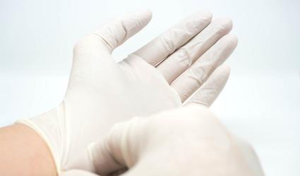 Wir betreuen Sie umfassend Ein Arzt zieht sich Einmalhandschuhe an.