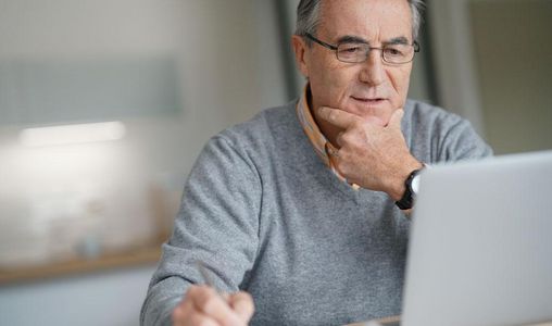 Mann sitzt am Laptop in der Küche