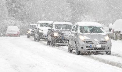 Unterwegs bei Schnee und Glätte Schneebedeckte Straße mit Fahrzeugen