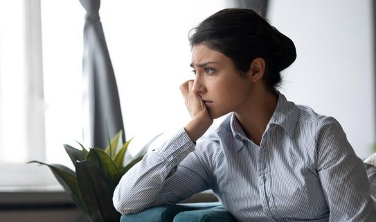 Die Pandemie raubt Energie Frau sitzt mit bedrücktem Gesichtsausdruck auf dem Sofa